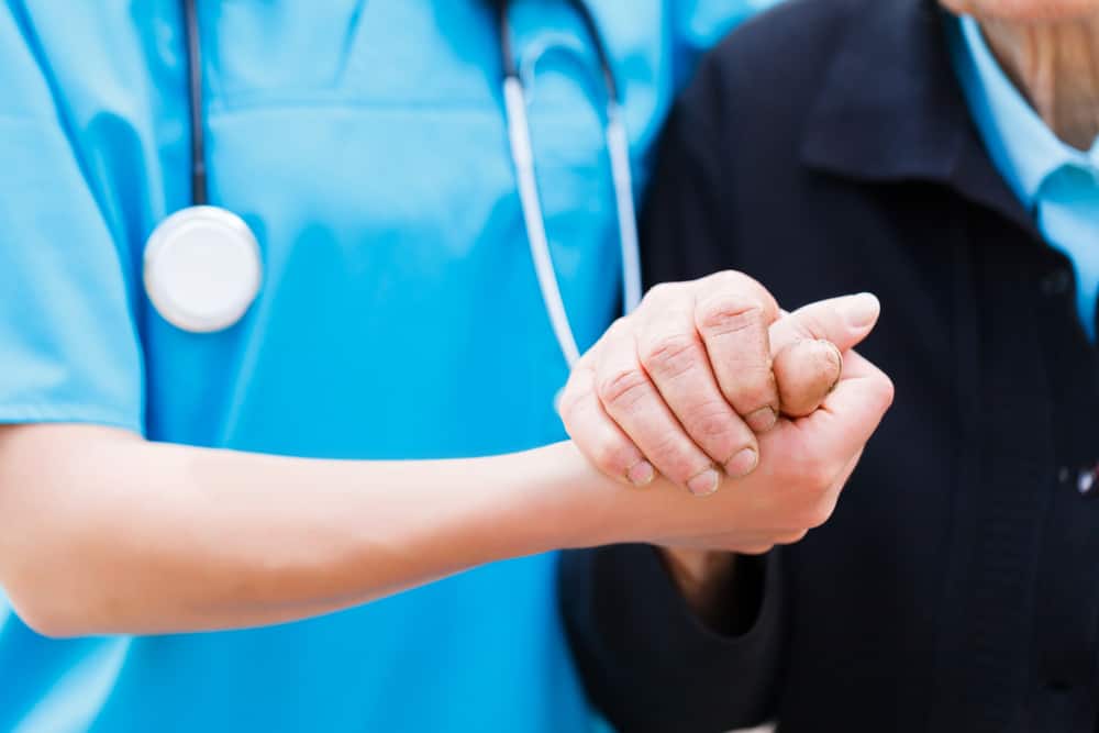 caregiver holding hands with elderly patient