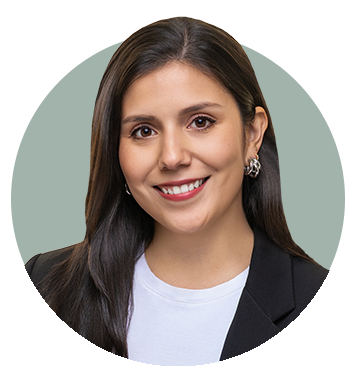 Professional headshot of a woman with long dark hair, wearing a black blazer and white top, smiling against a muted green background.